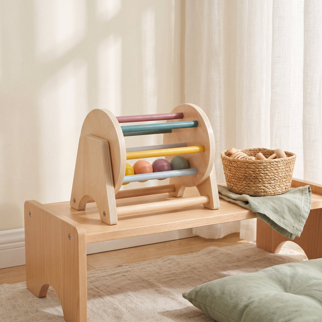 Wooden rolling drum toy on a low Montessori shelf in a calm playroom