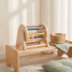 Wooden rolling drum toy on a low Montessori shelf in a calm playroom