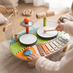 A toddler's hand tapping the big drum of the wooden music table with a mallet