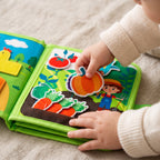A toddler's hand placing the felt pumpkin on the vegetable garden page