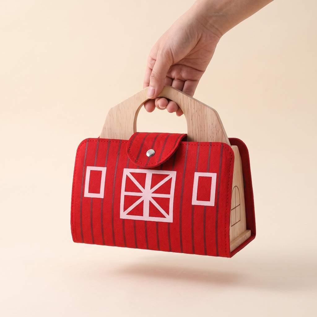 Wooden farm barn folded into its red felt carry case