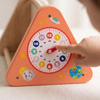 Close-up of a child's finger moving the hand of the wooden teaching clock