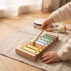 A child's hands playing the pastel wooden xylophone with a mallet