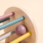 Close-up of the smooth plywood edge and pastel dowels of the wooden rolling drum toy