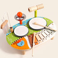 Wooden music table toy with two drums, xylophone, cymbal, wind chimes, tone block and castanet on a cream background