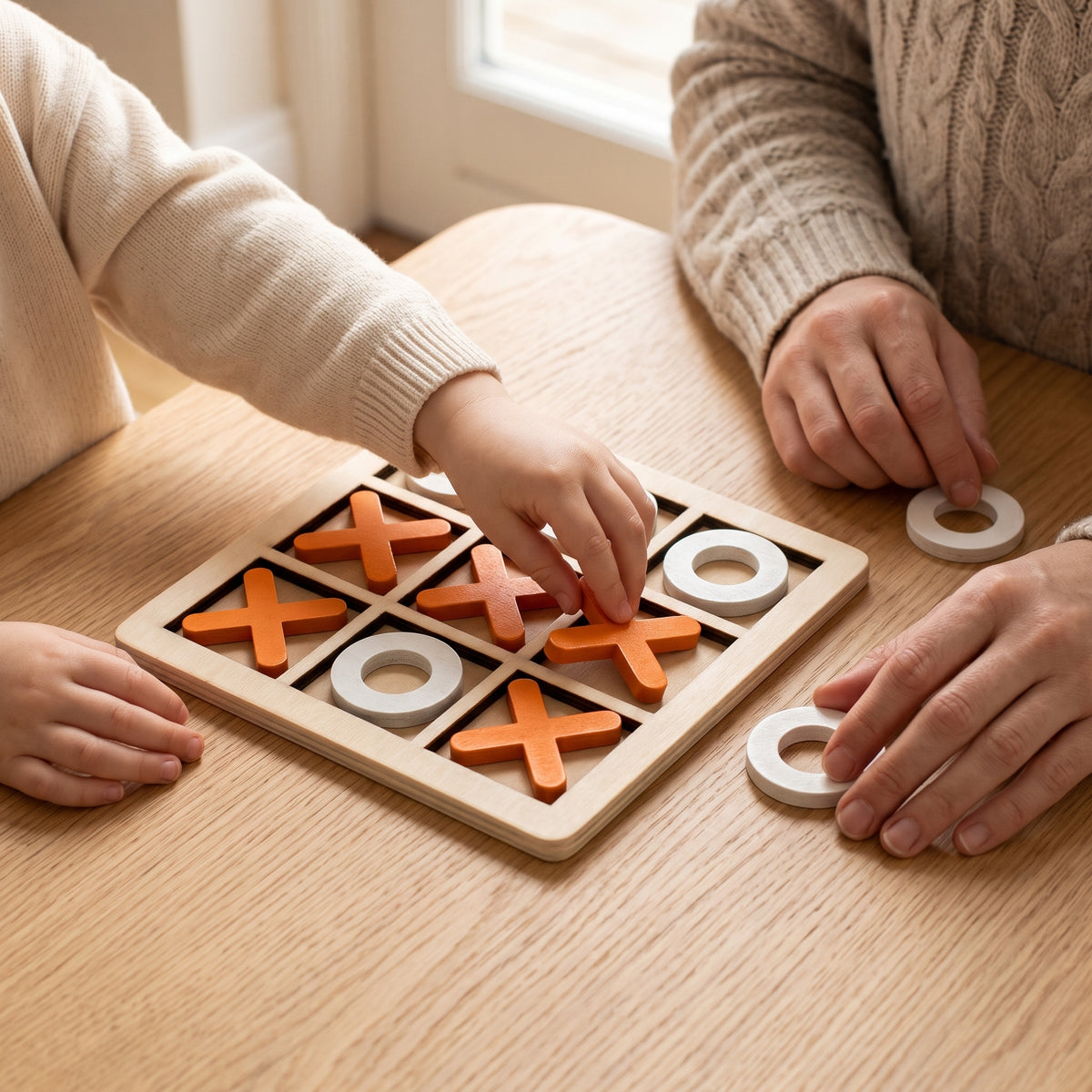 A parent and child playing wooden noughts and crosses together