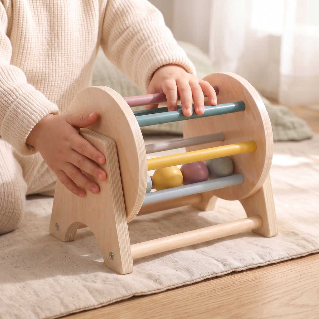 A child's hands turning the wooden rolling drum toy on a linen play mat