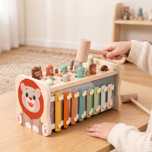 A child's hand tapping a wooden mole with the hammer