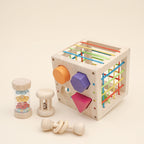 Wooden shape sorter cube with rainbow cords and three wooden baby rattles