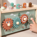 Close-up of a child's finger turning the wooden gears on the back of the bench