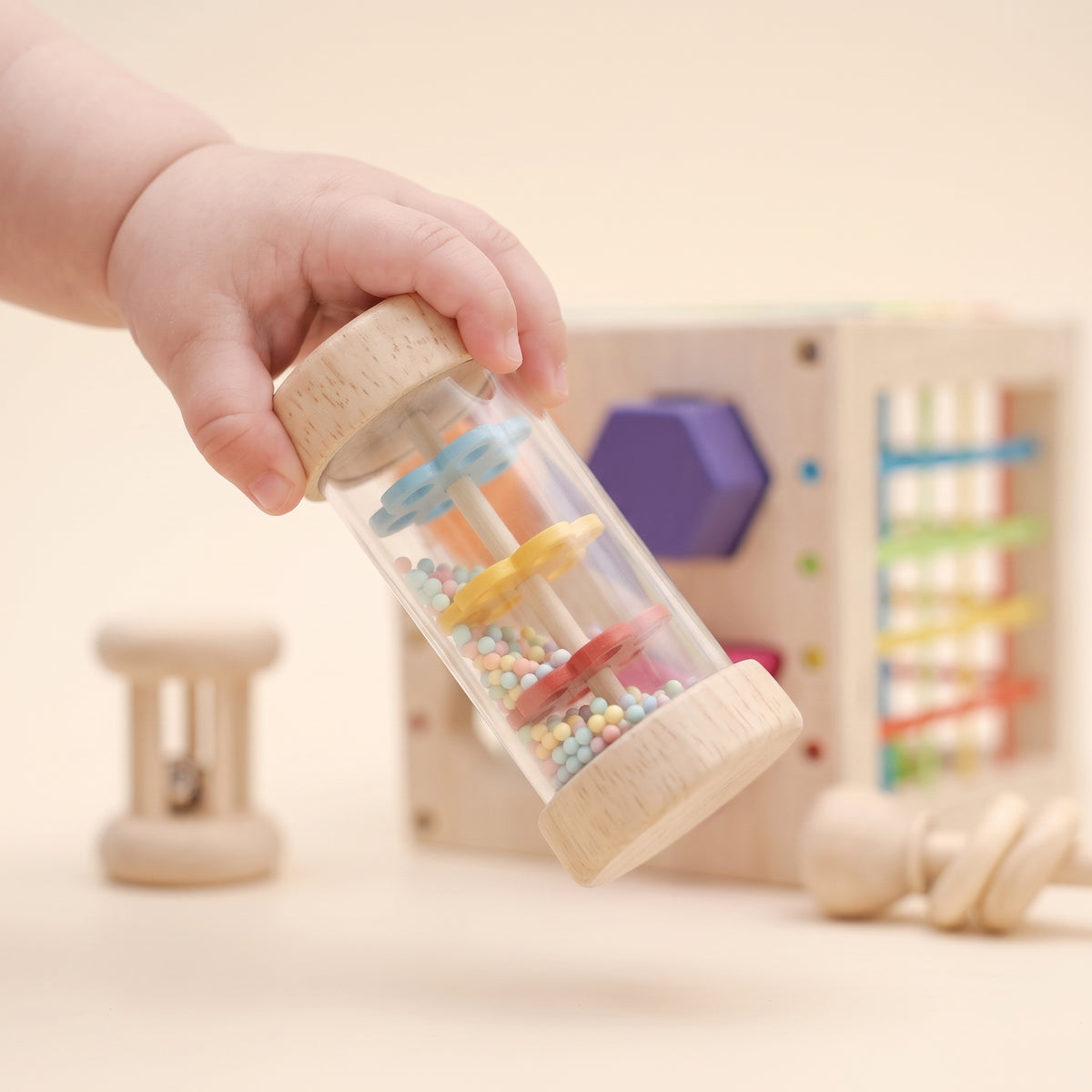 Baby holding the wooden rain-stick rattle