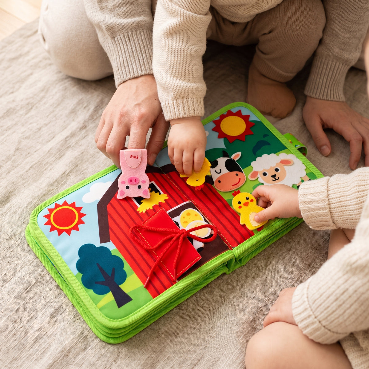 A parent and toddler playing with the felt finger puppets of the farm cloth book