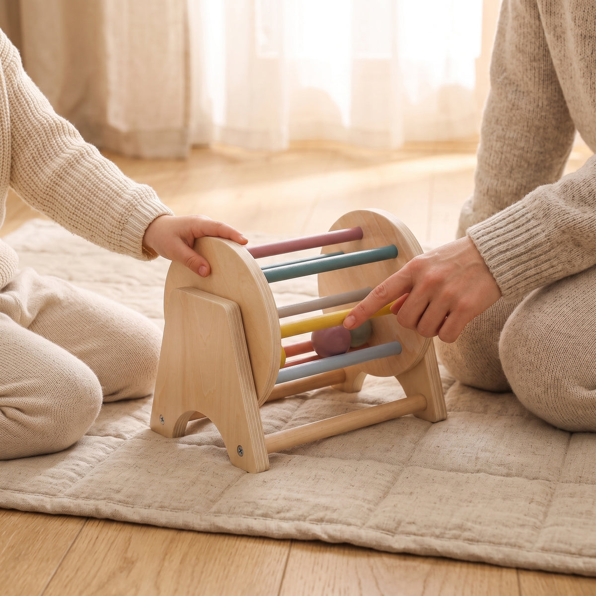 A parent pointing at the coloured wooden balls of the rolling drum while a child turns it